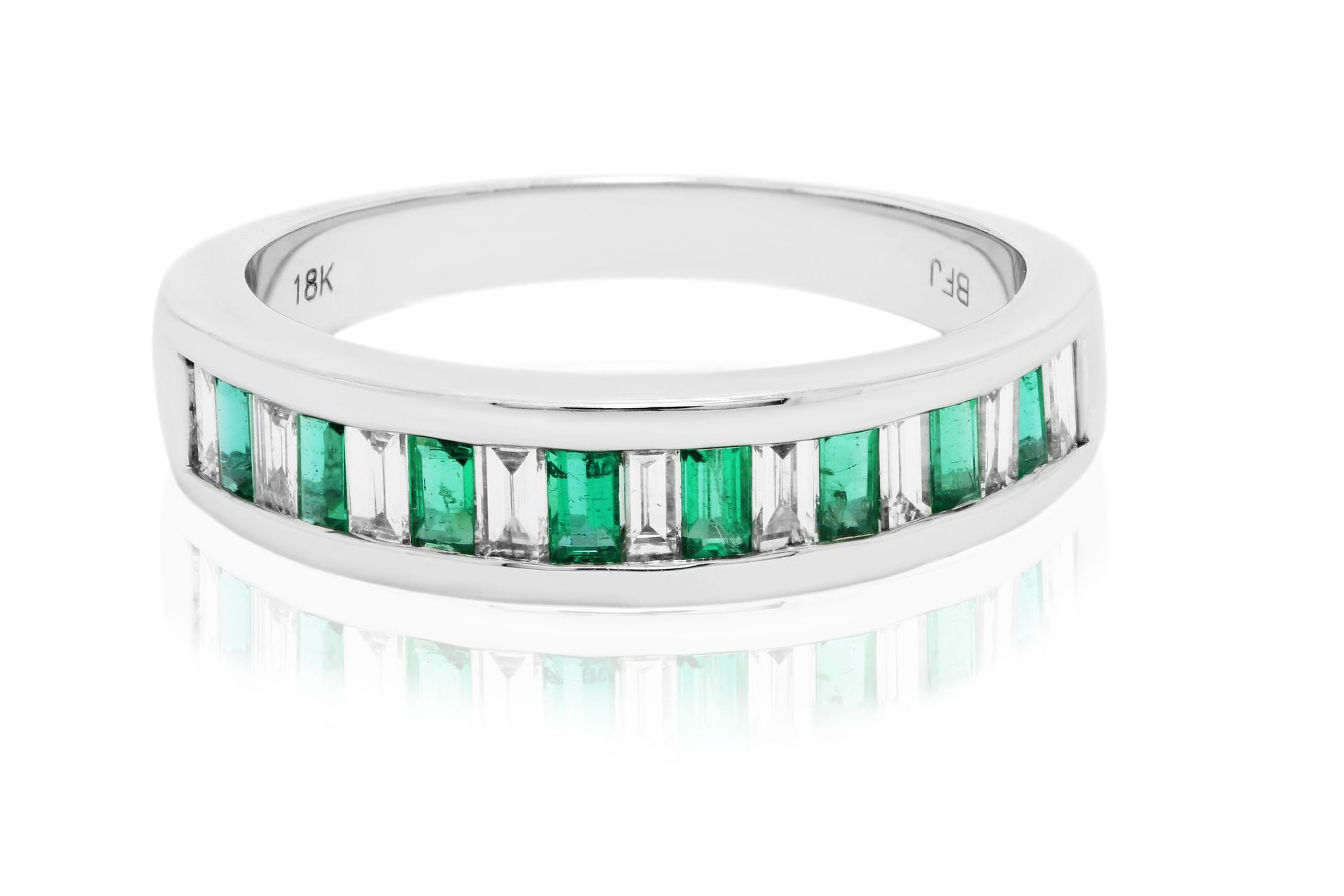 White ring with rectangular green gemstones in a channel setting, displayed on a white background