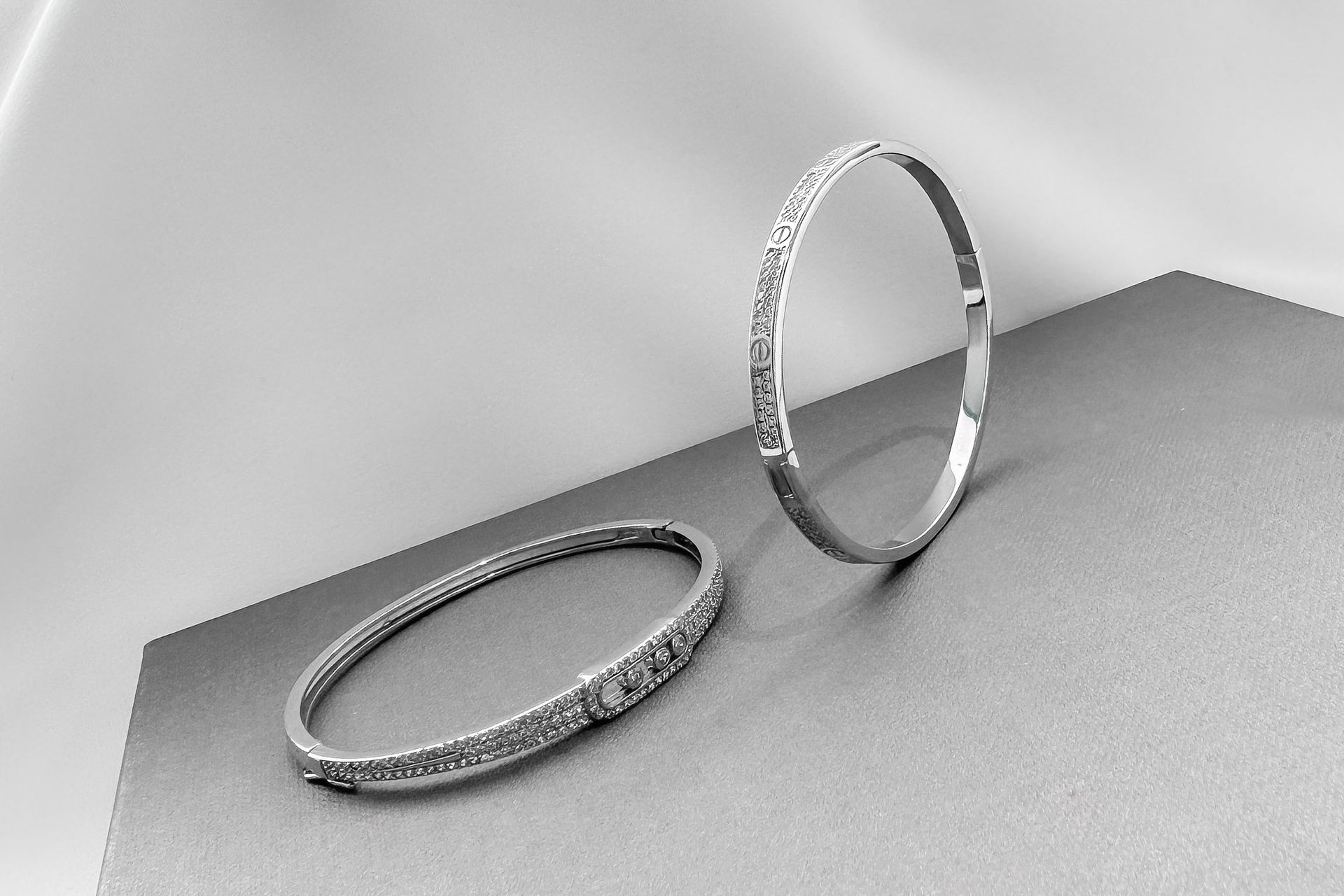 Two silver rings on a gray surface, one standing upright and one lying flat