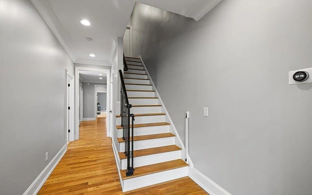 Hallway with wooden floor, stairs, and gray walls.