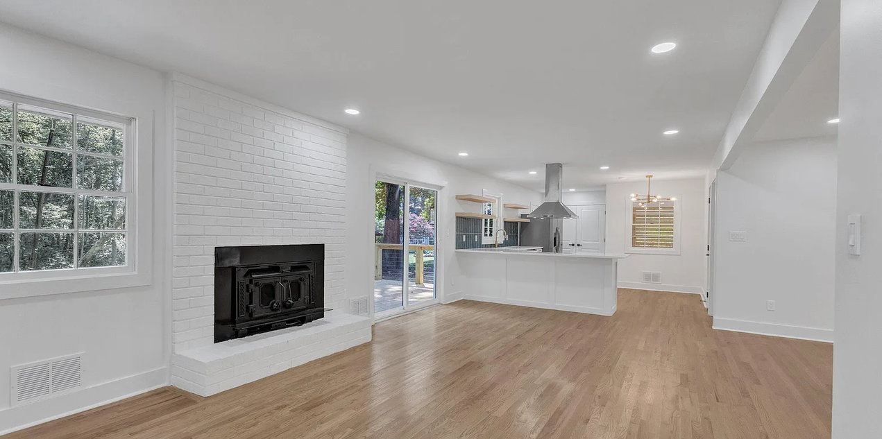 A bright, modern living space with a white brick fireplace and kitchen island.