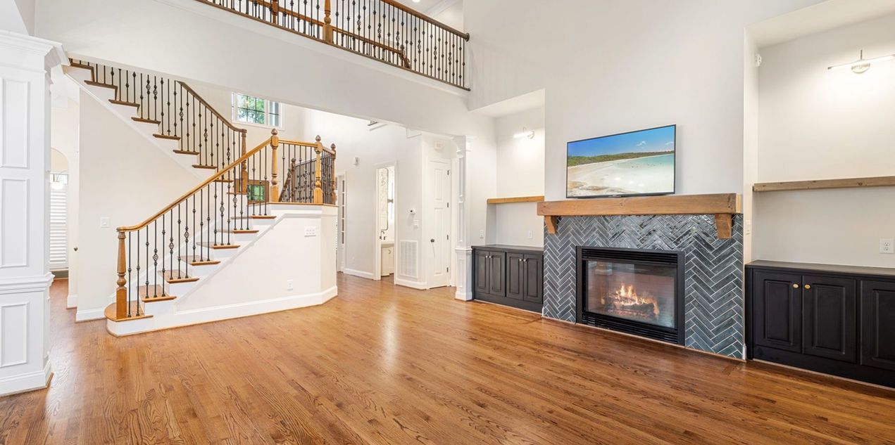 Spacious living room with hardwood floors, a fireplace, staircase, and a loft area.