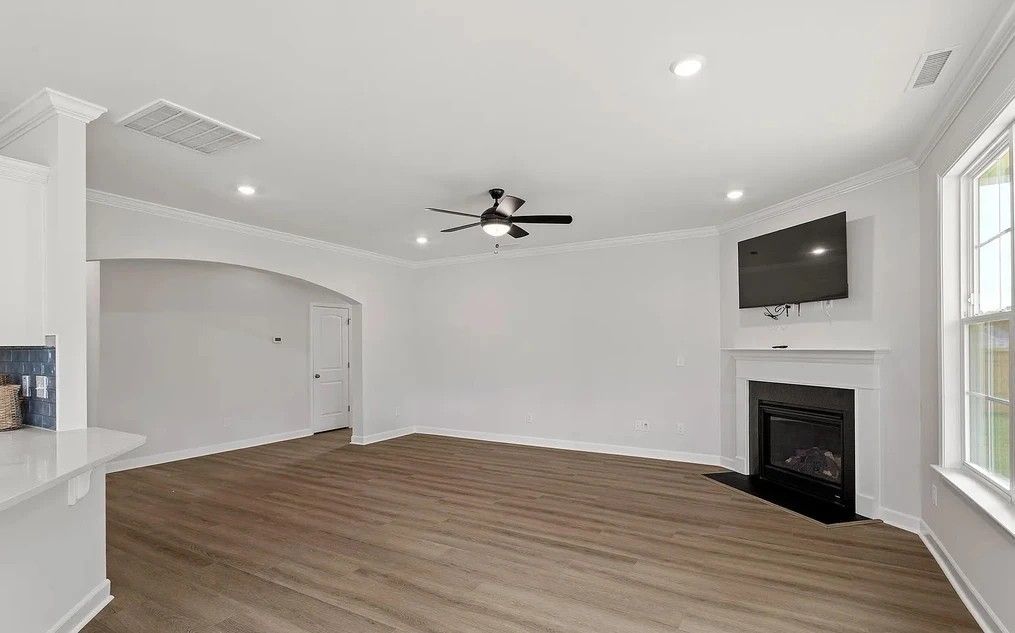 Empty living room with fireplace, TV, and hardwood floors.