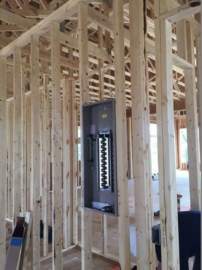 Electrical panel installed within the wooden framework of a new home under construction.