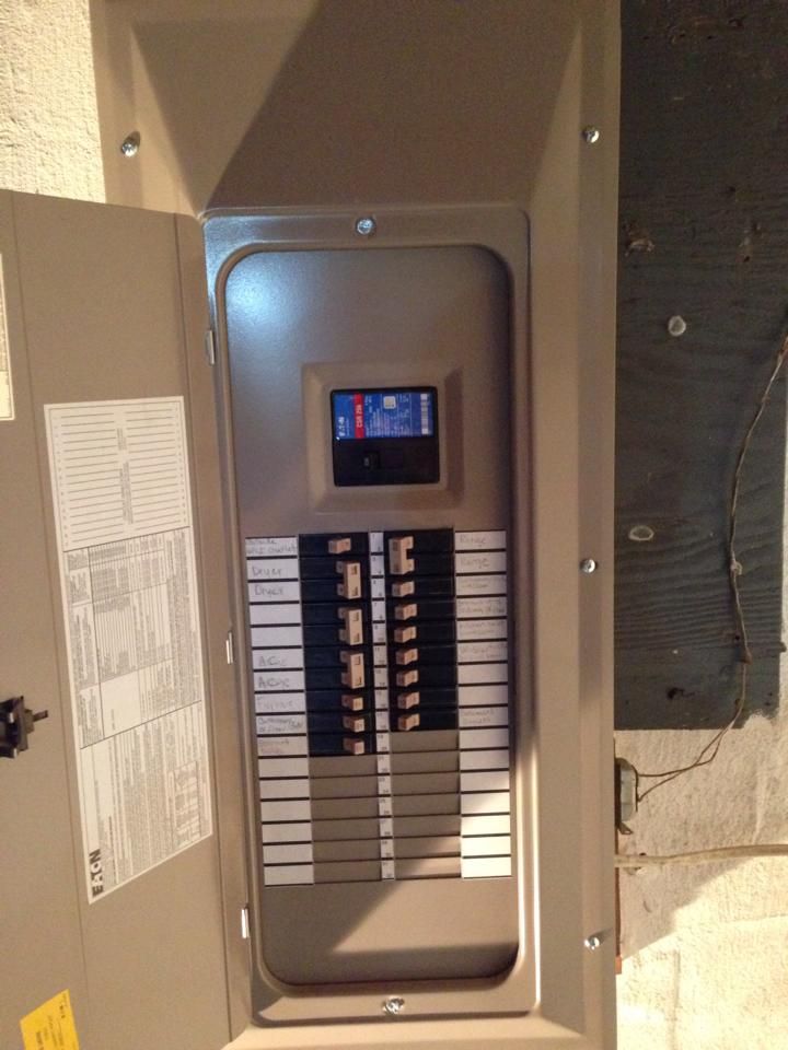 Open electrical circuit breaker box with switches in a beige metal cabinet.