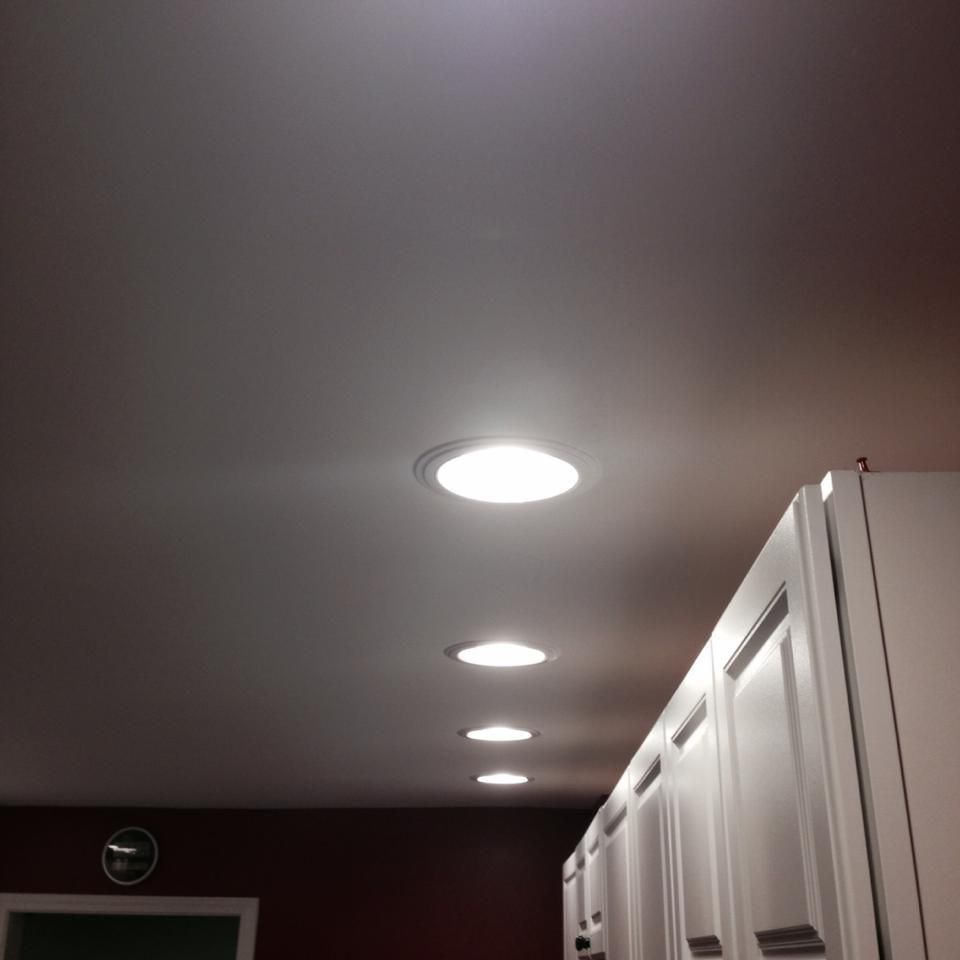 Overhead kitchen lights illuminate the ceiling. White cabinets line the right.