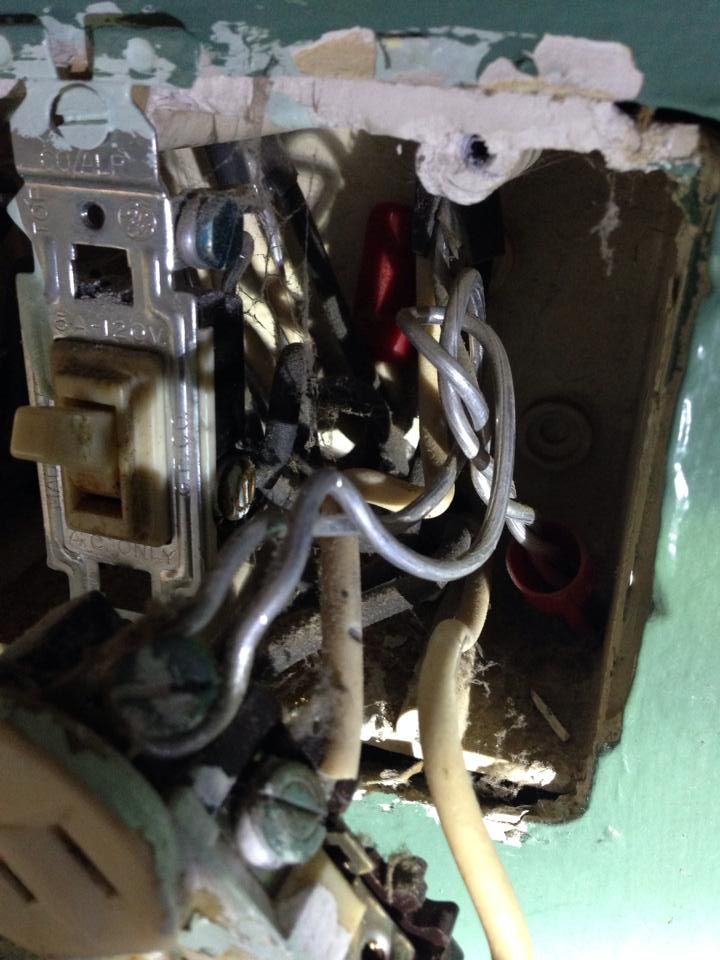 Electrical wiring inside a wall. Exposed wires, a light switch, and a damaged box are visible.