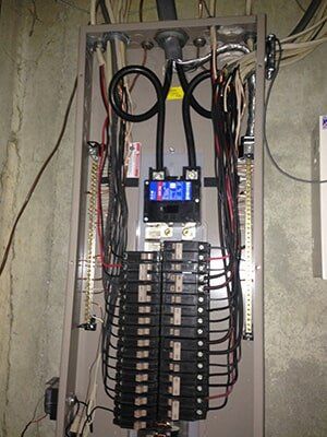 Electrical panel with multiple circuit breakers and wiring.