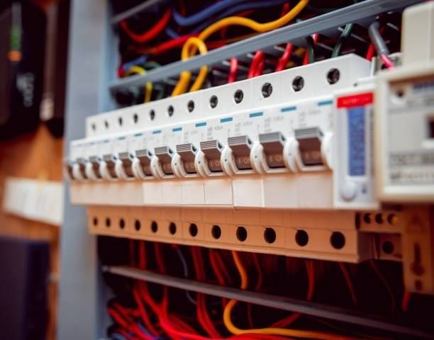 Electrical panel with rows of circuit breakers and colorful wires.
