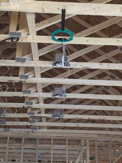 Wooden ceiling with recessed lighting fixtures and electrical wiring during construction.