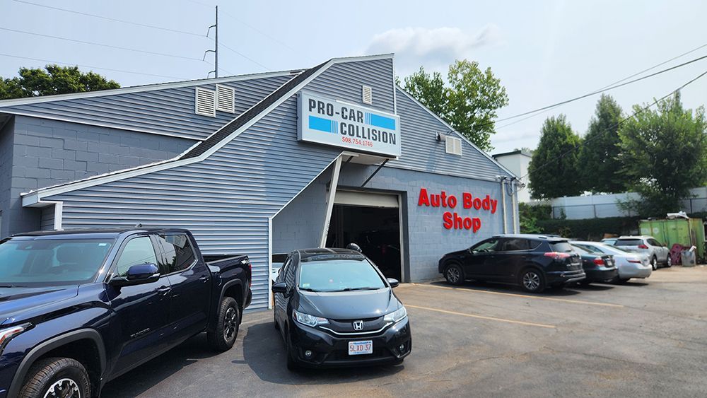 A row of cars are parked in front of an auto body shop.