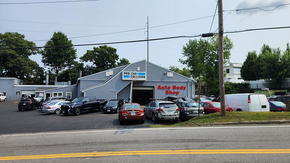 A lot of cars are parked in front of an auto body shop