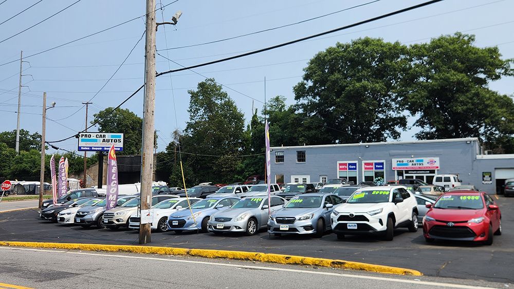 A lot of cars are parked in front of a car dealership.