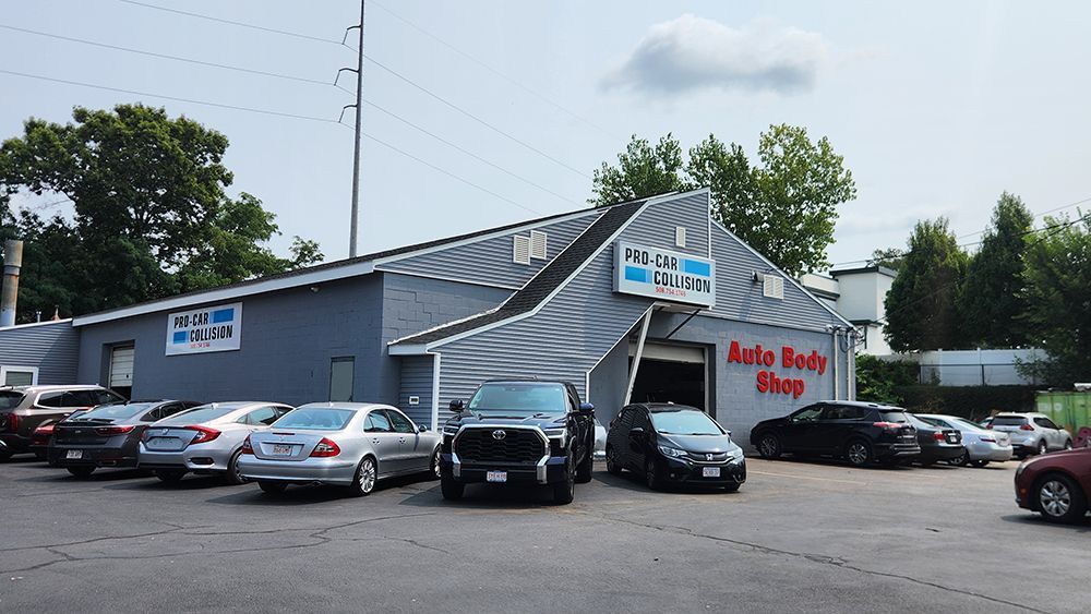 A lot of cars are parked in front of an auto body shop