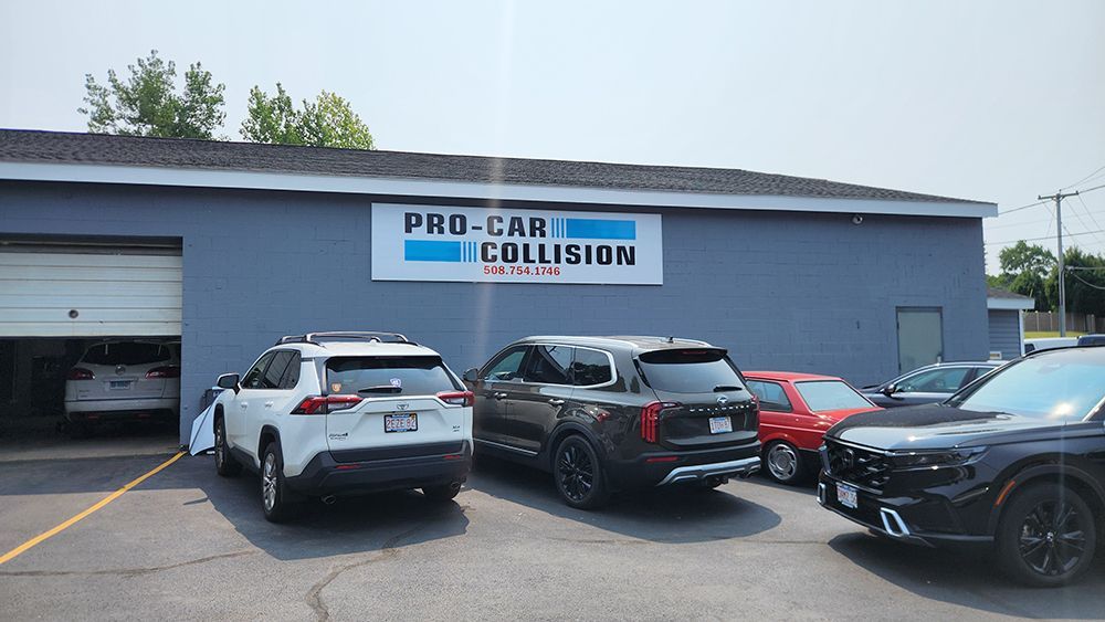 A group of cars are parked in front of a pro-car collision repair shop.