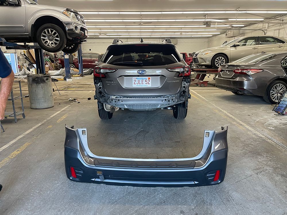 A subaru outback is being repaired in a garage.