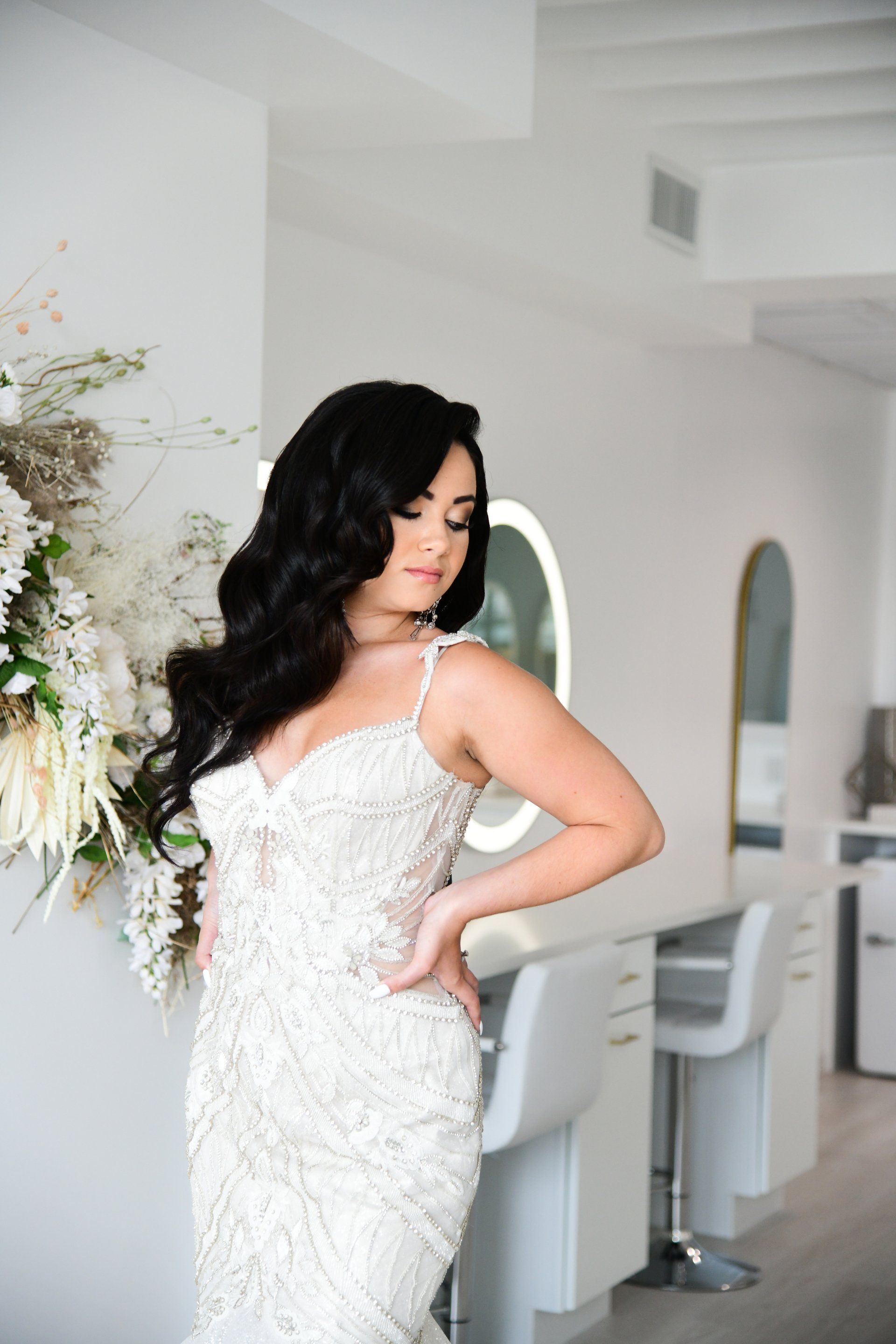 Woman in a white beaded gown, hair styled, in a salon.