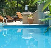 A large swimming pool surrounded by chairs and trees.