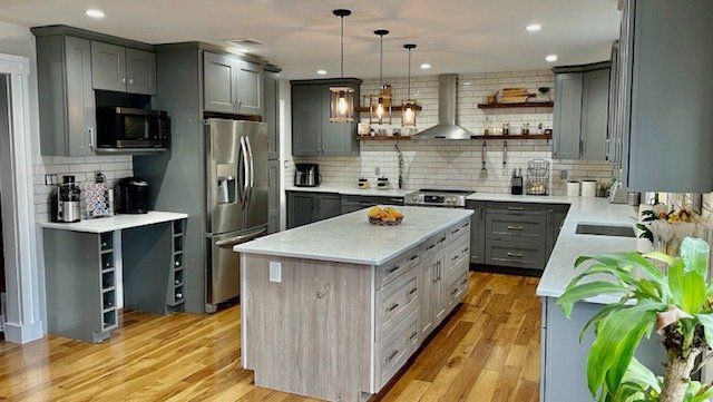 A kitchen with gray cabinets and a large island in the middle.