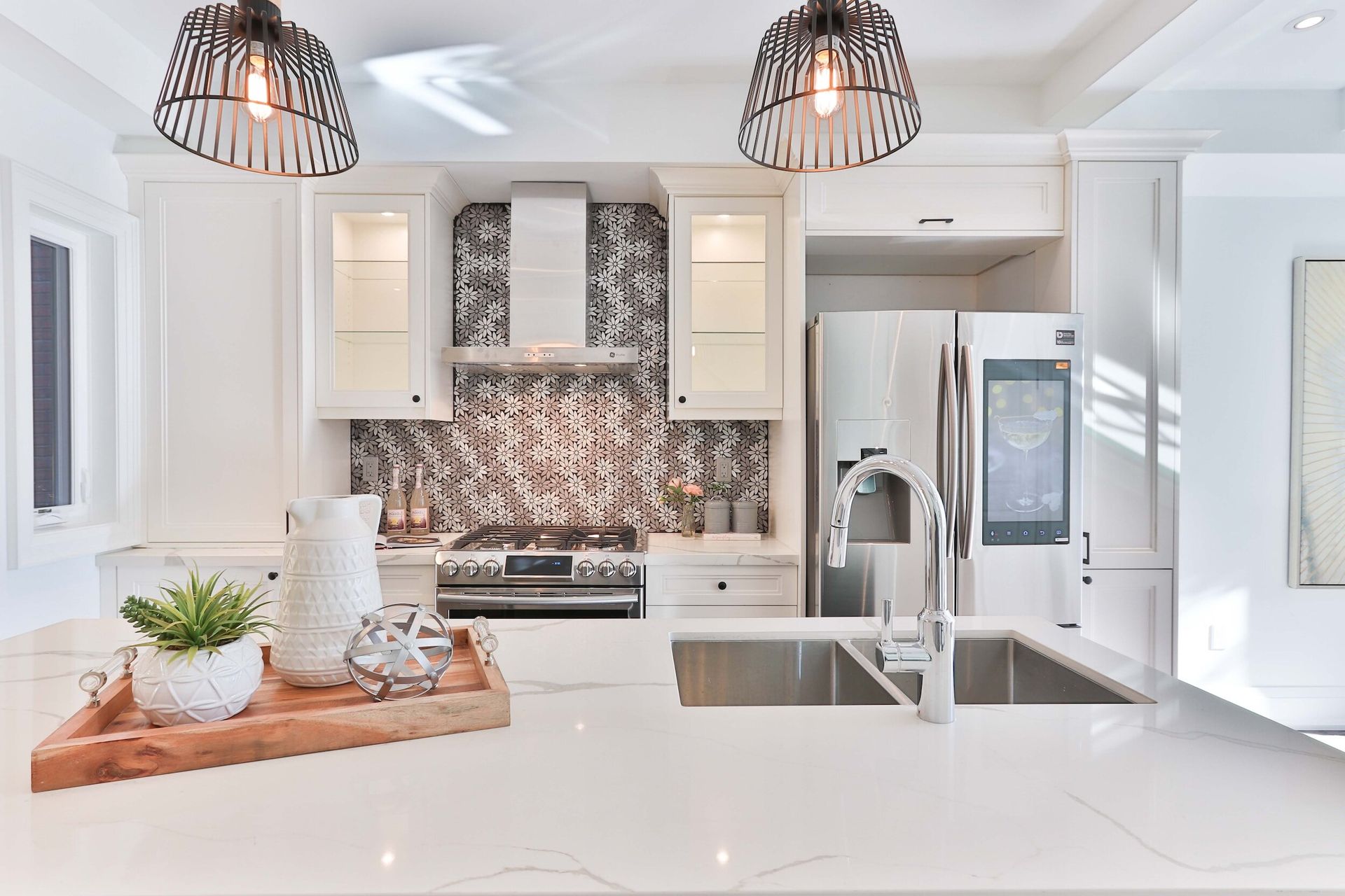 A kitchen with white cabinets , a stainless steel refrigerator , a sink , and a stove.