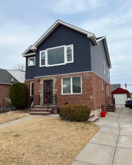 A brick house with a blue siding and white windows