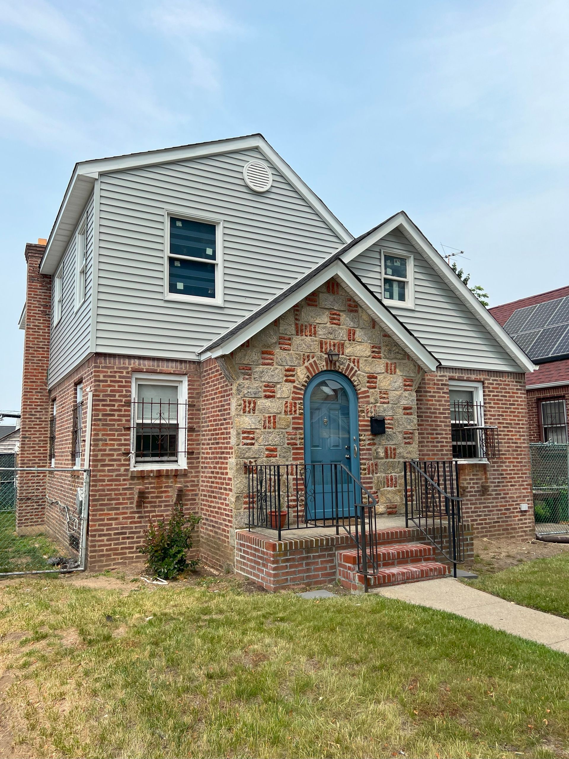 A brick house with a white roof and a blue door.
