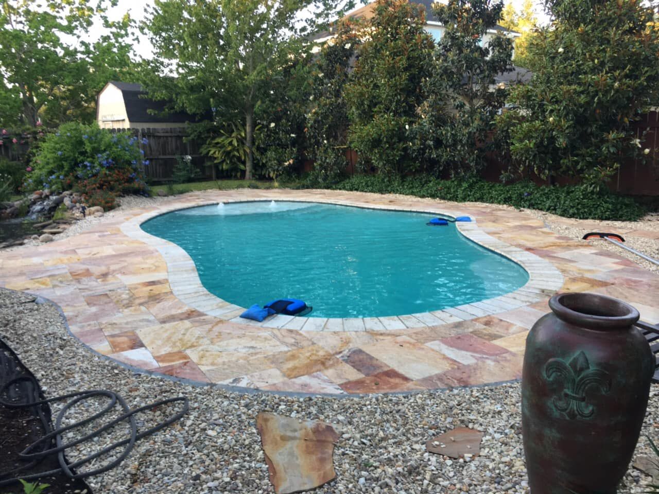 Circular in-ground pool with travertine surrounded in a private backyard in Lutcher, LA
