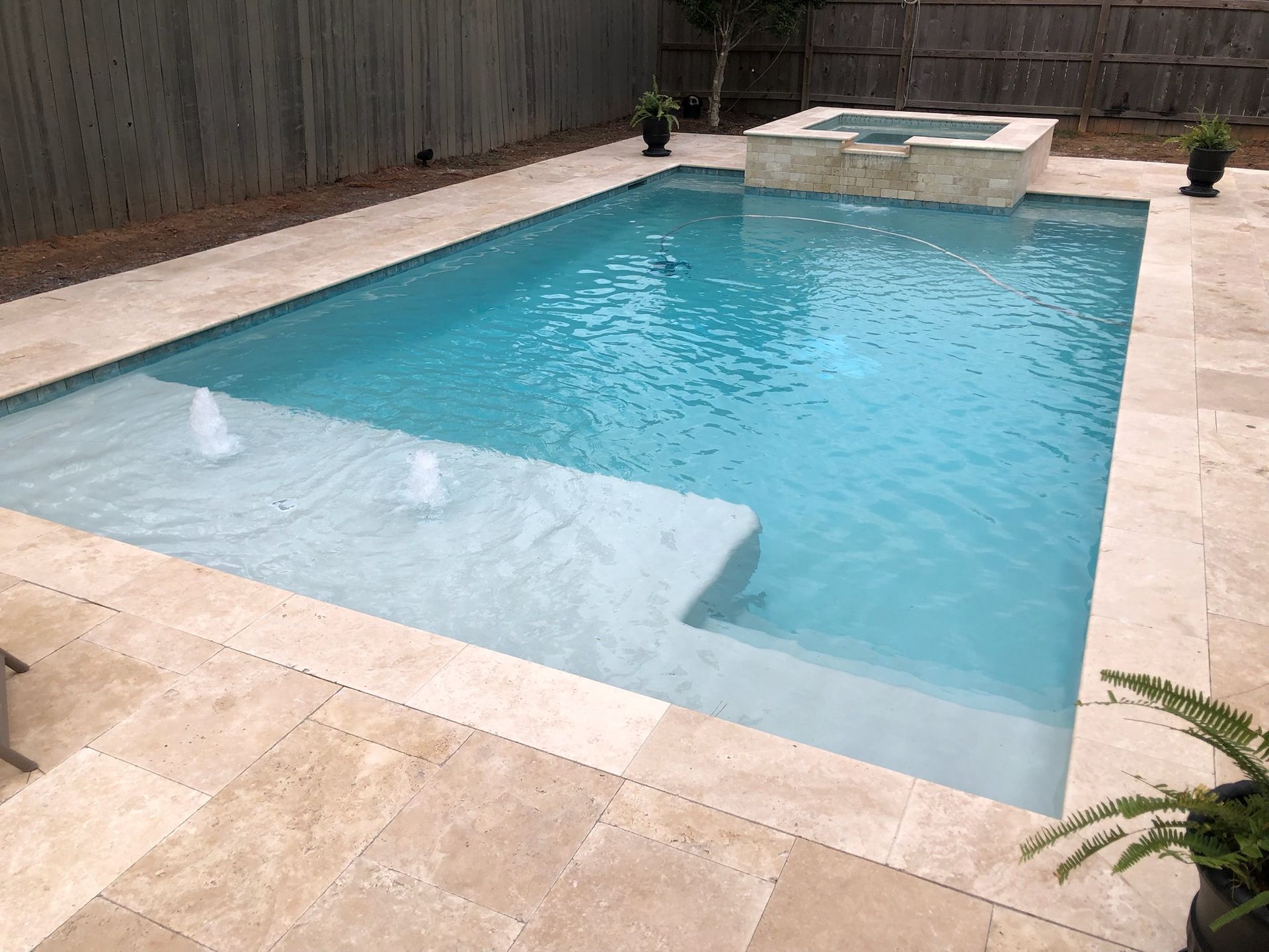 Backyard in-ground pool with attached hot tub and travertine patio in Harahan, LA