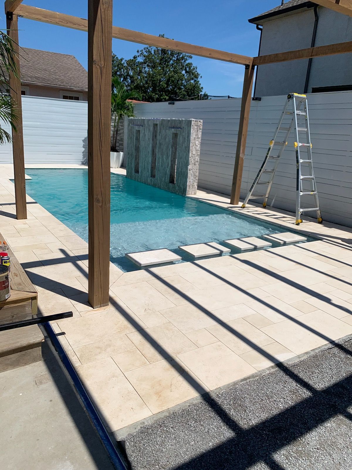 Shaded in-ground pool area with pergola beams in Chalmette, LA