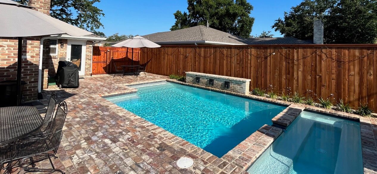 Swimming pool with brick pavers and wood fence in Gretna, LA