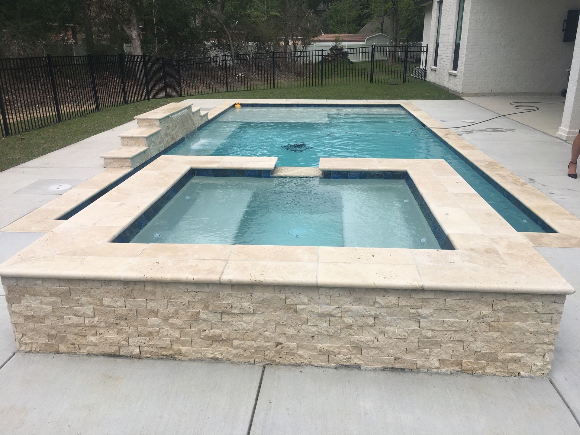 Square spa inside modern rectangular pool in Covington, LA backyard