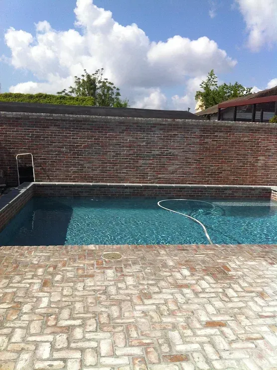 Modern pool surrounded by brick wall and patio in Harahan, LA