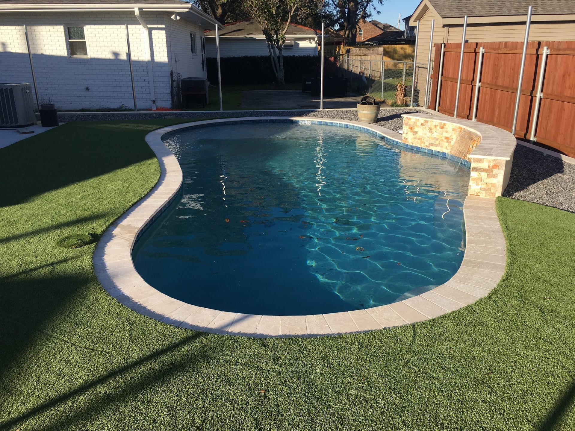 Curved pool surrounded by artificial turf in Marrero, LA