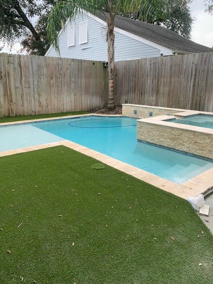 Private pool with raised wall and wood fencing in backyard in Luling, LA