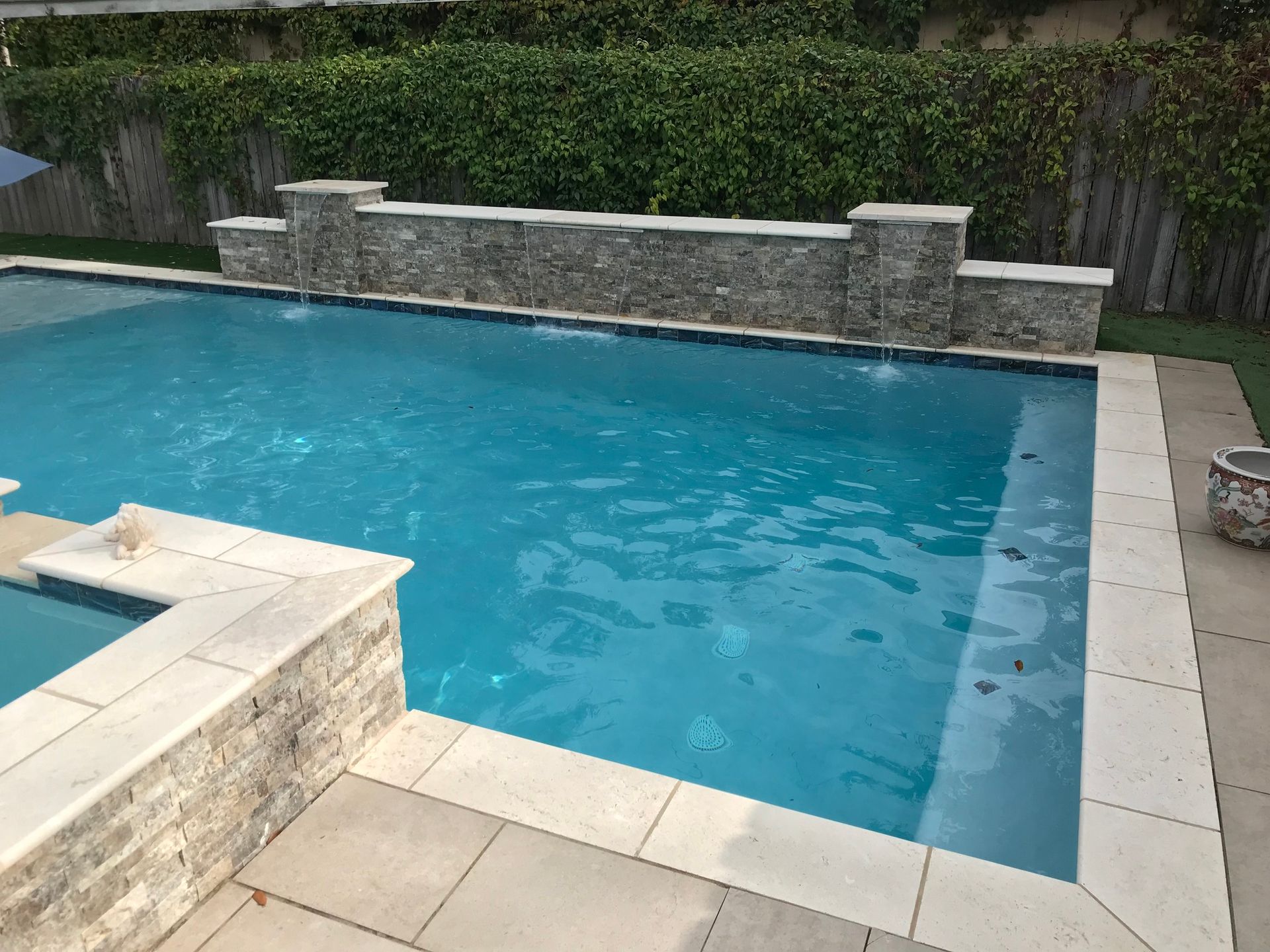 Rectangular pool with stone wall water feature in backyard in Destrehan, LA
