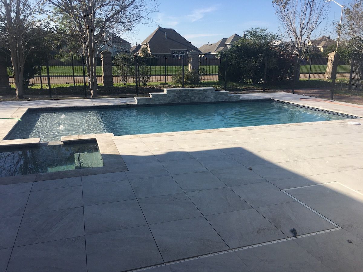 Modern in-ground pool with spa and waterfall feature in backyard in Zachary, LA