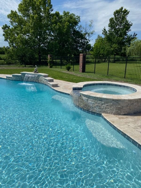 In-ground pool with raised hot tub and waterfall feature in the center in Mandeville, LA
