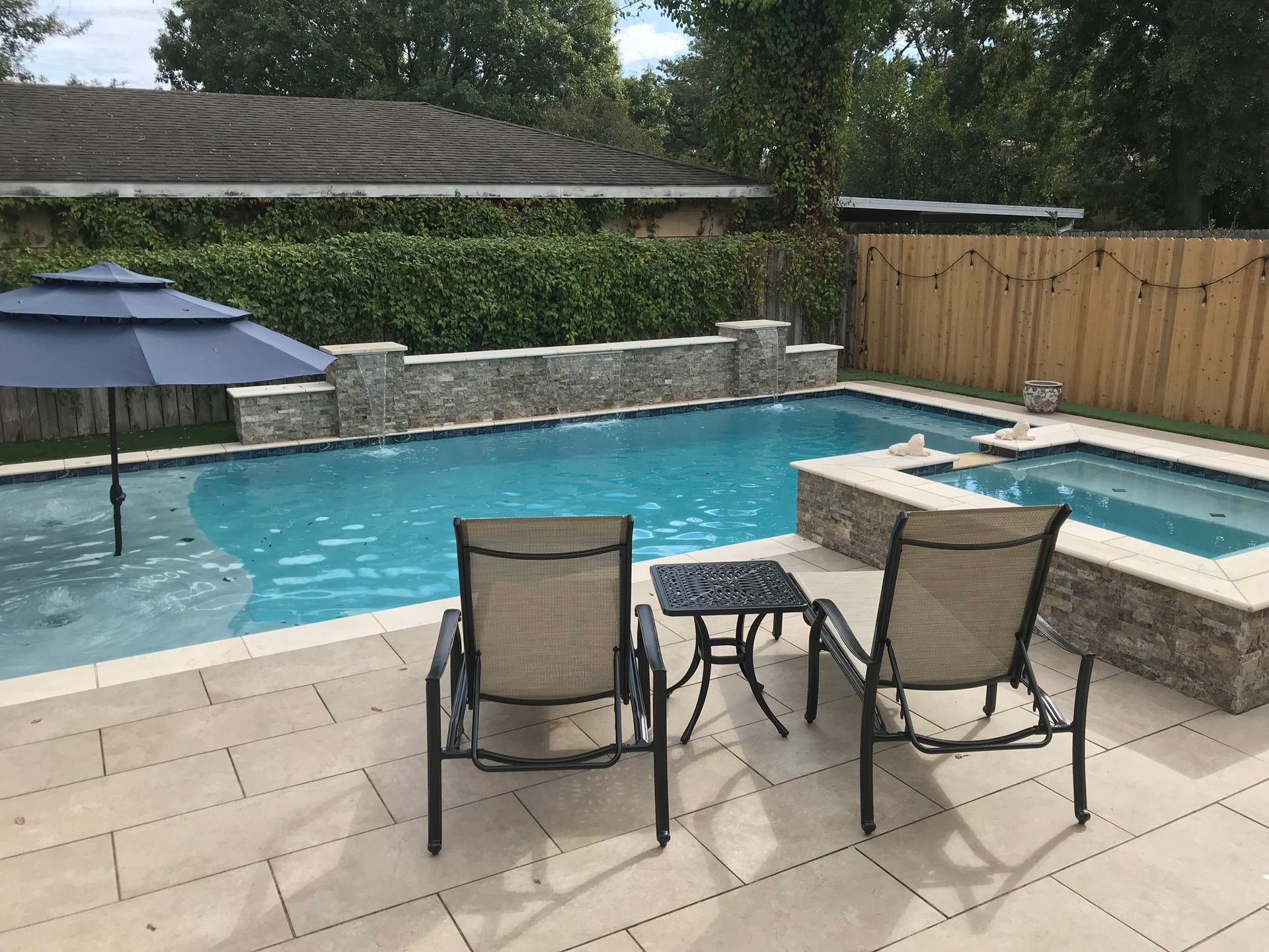 Two chairs beside spa and pool with stonework features in Belle Chase, LA