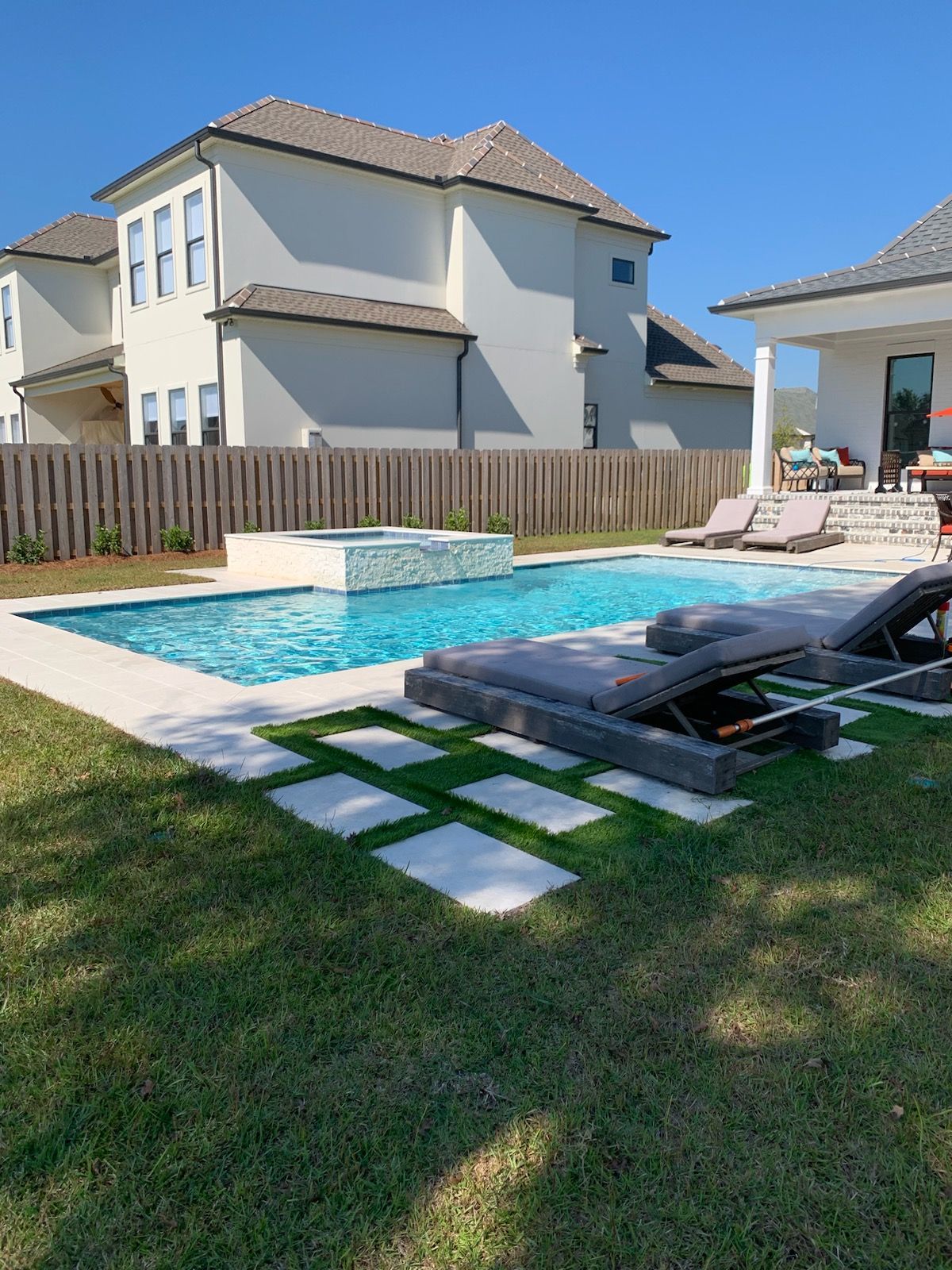 Modern in-ground pool with lounge chairs and geometric stepping pads in Madisonville, LA