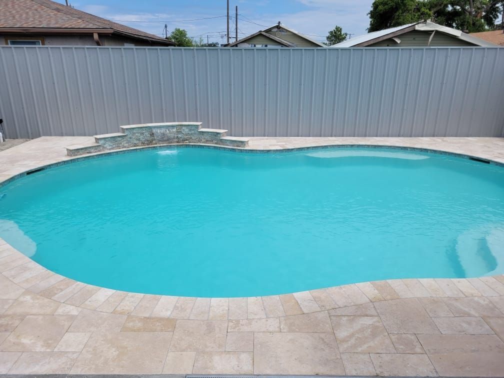 Oval-shaped swimming pool with raised seating wall in Springfield, LA
