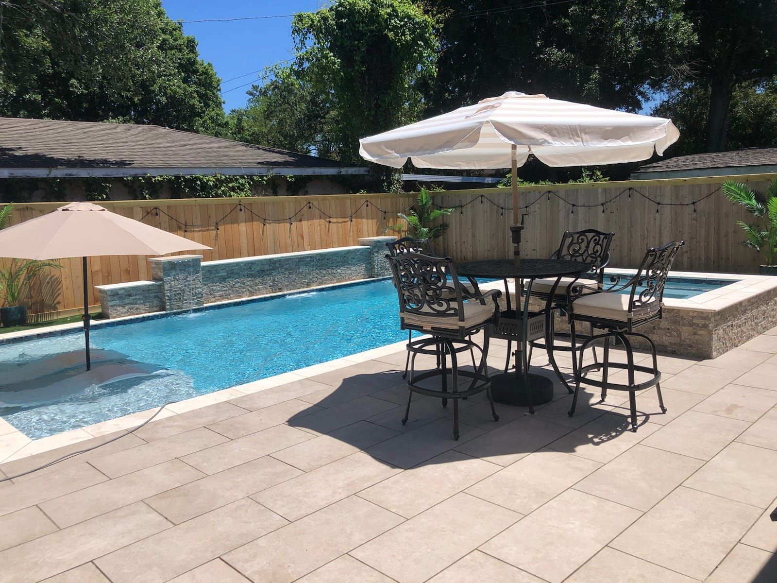 Patio with umbrella, table, and chairs next to swimming pool in Thibodaux, LA