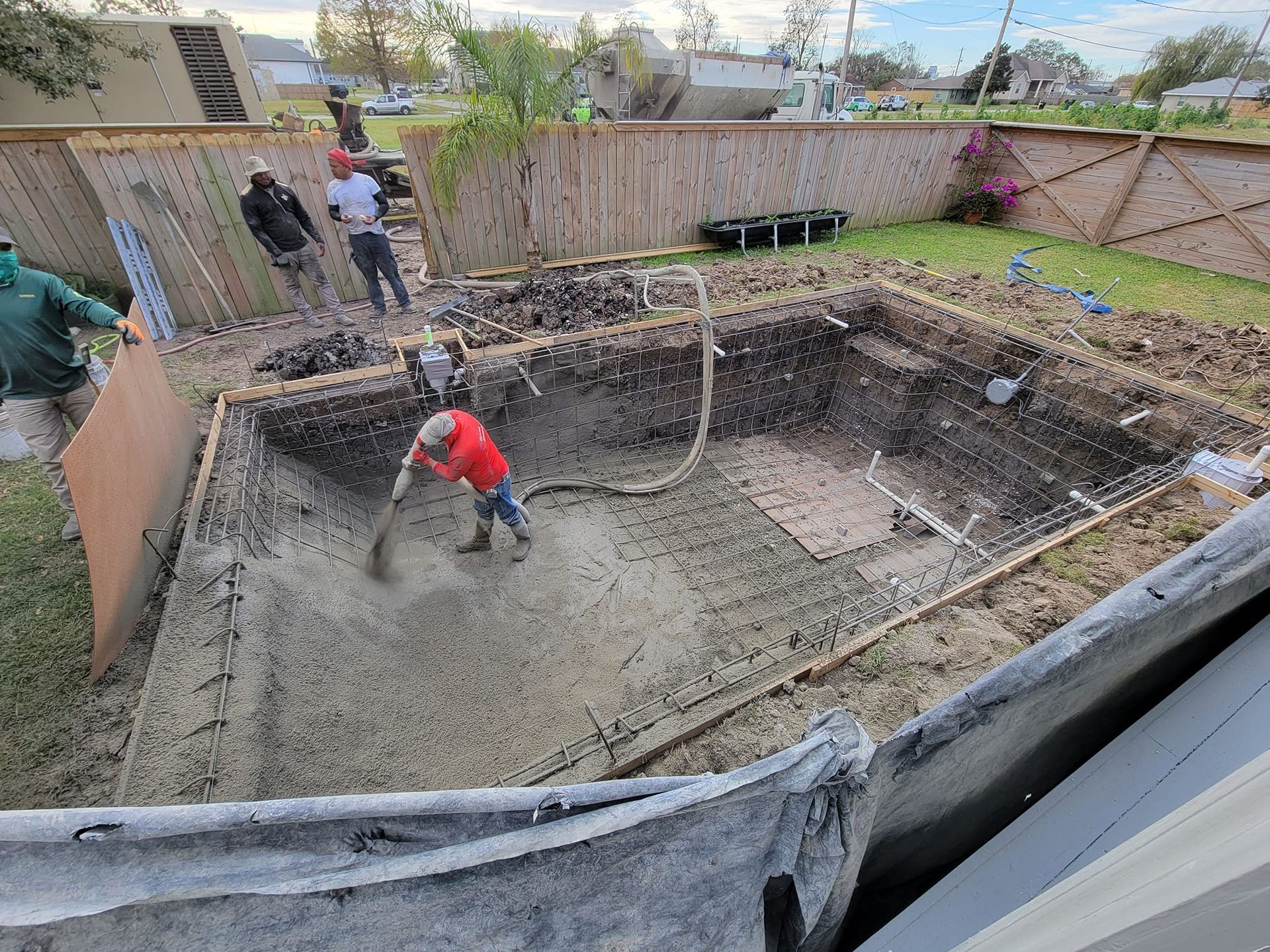 Gunite being sprayed by crew during pool build in Slidell, LA backyard