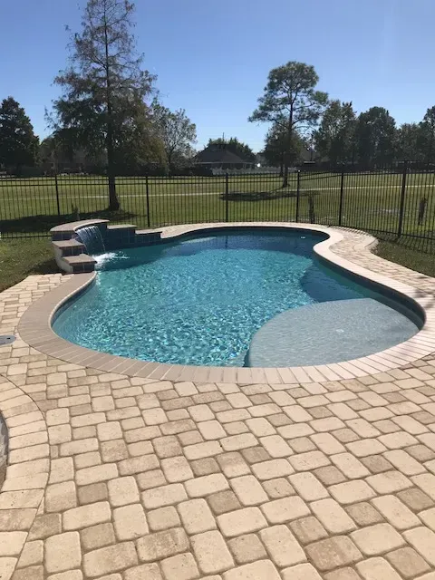 Swimming pool with travertine brick pavers in Prairieville, LA