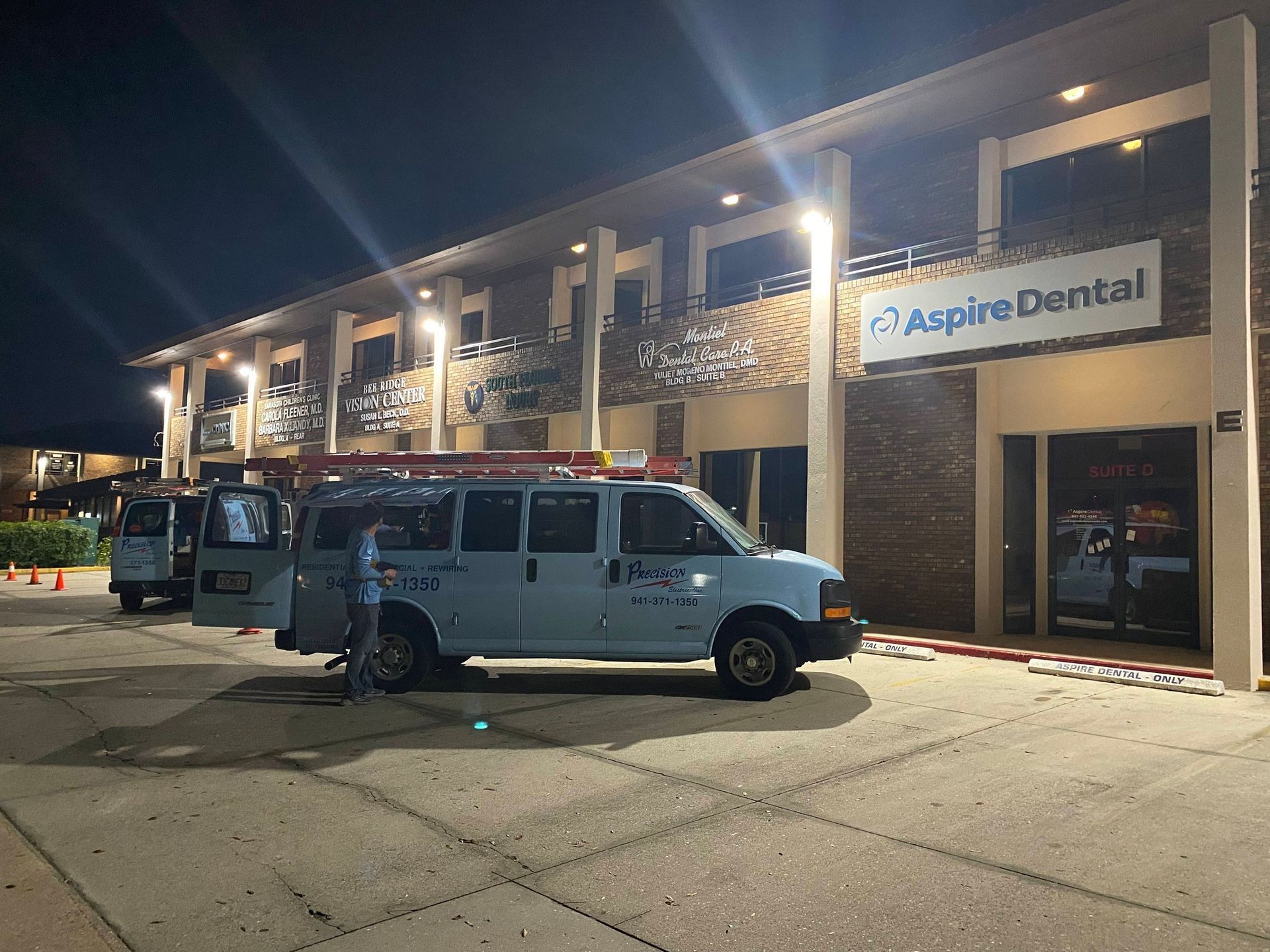 Nighttime outside Aspire Dental, with a white van parked under bright lights by the entrance.