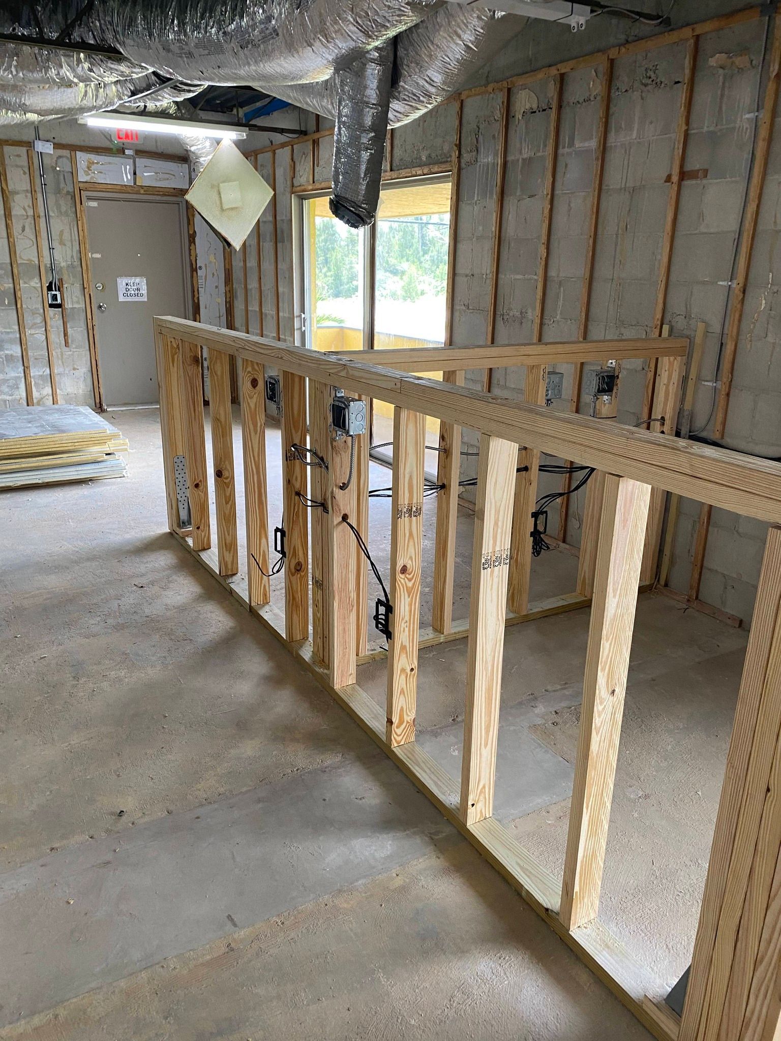 Unfinished basement interior with exposed framing, insulation, and a stair railing under construction.