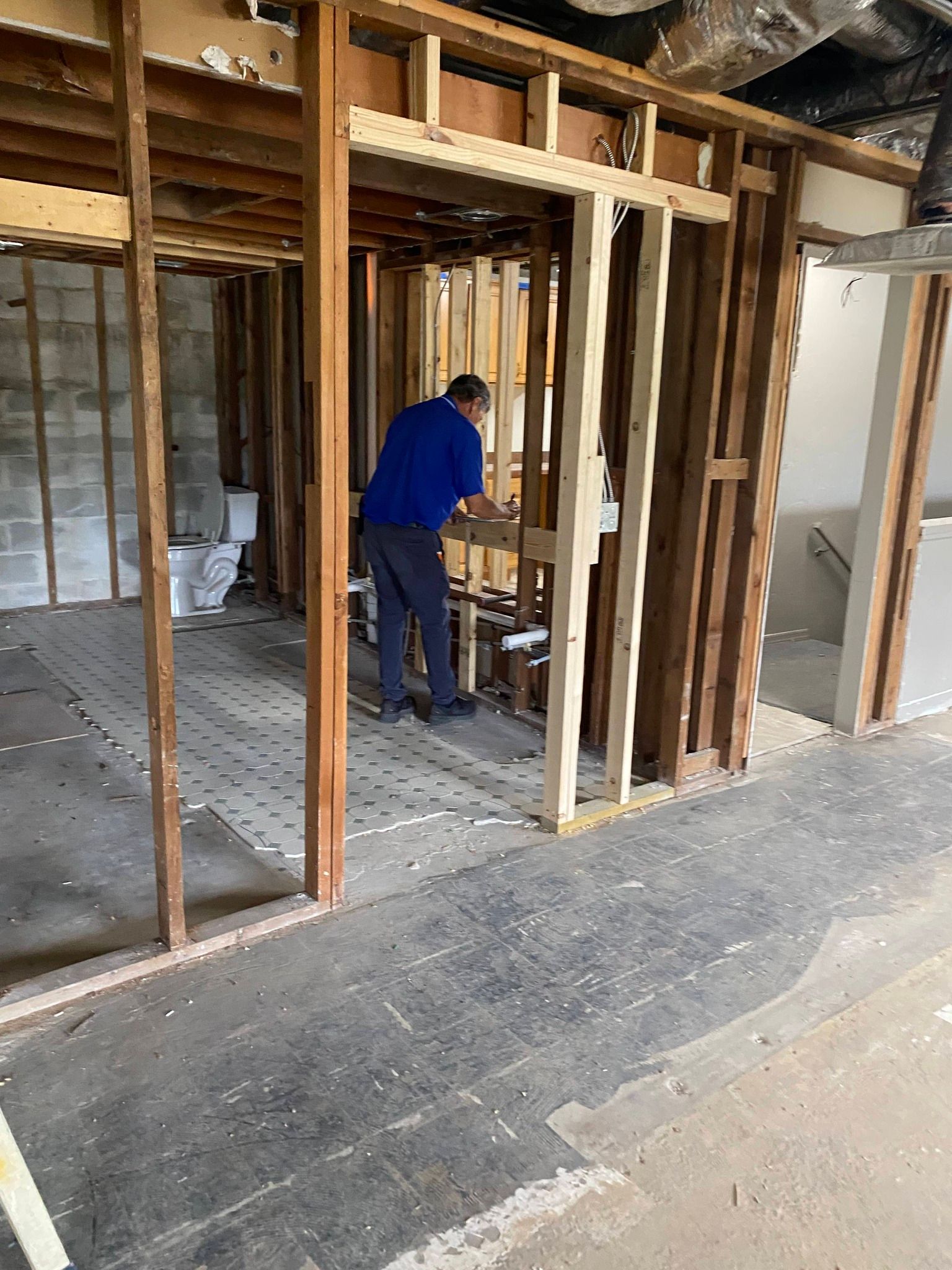Worker in blue shirt framing an interior wall during home renovation.
