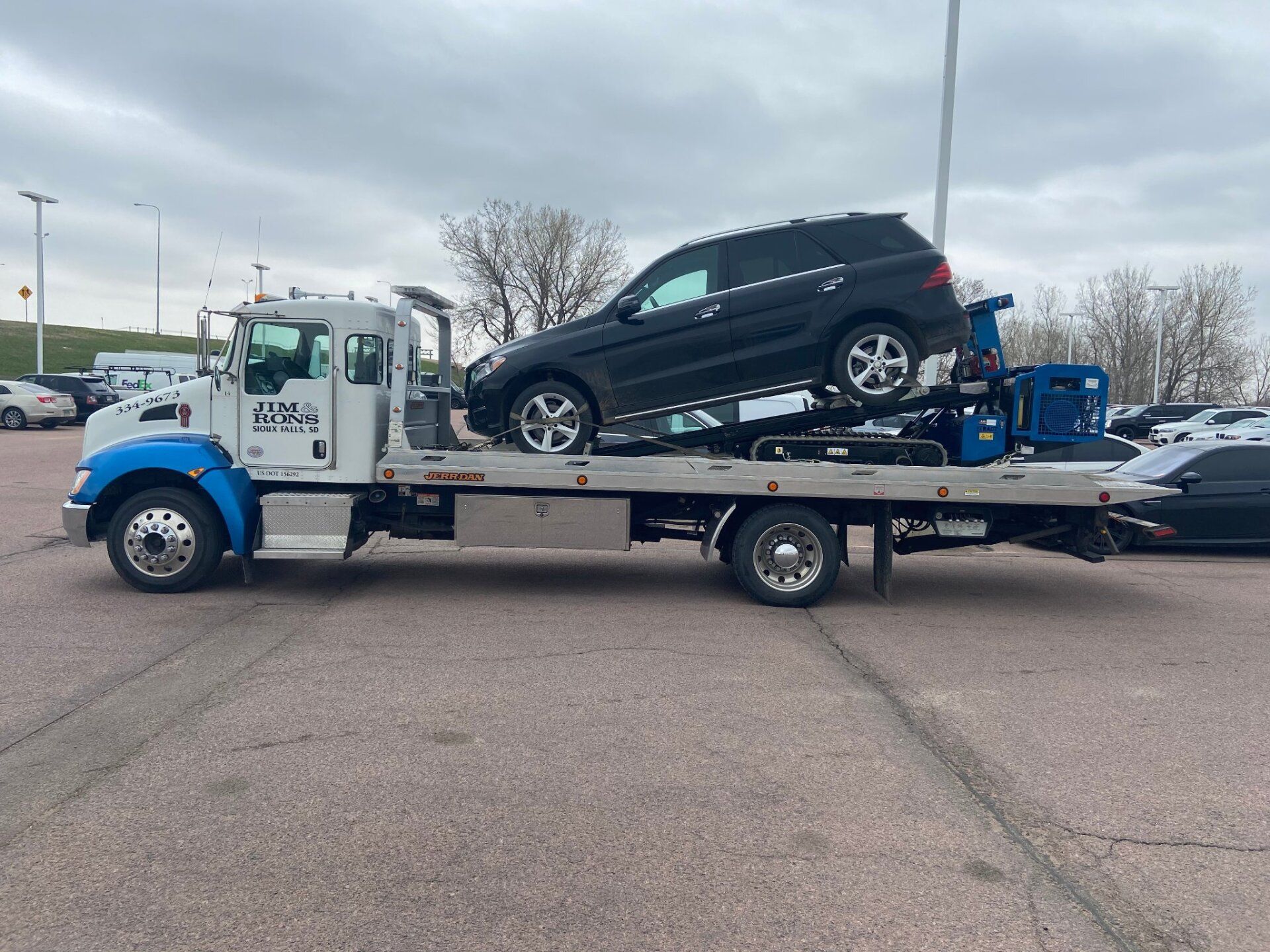 A tow truck is carrying a suv on the back of it.