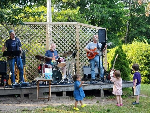 A group of people are playing instruments on a stage while children watch.