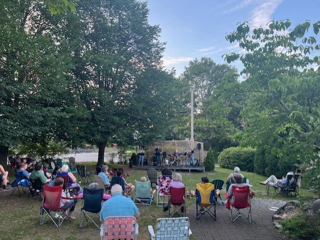 A group of people are sitting in folding chairs in front of a stage.