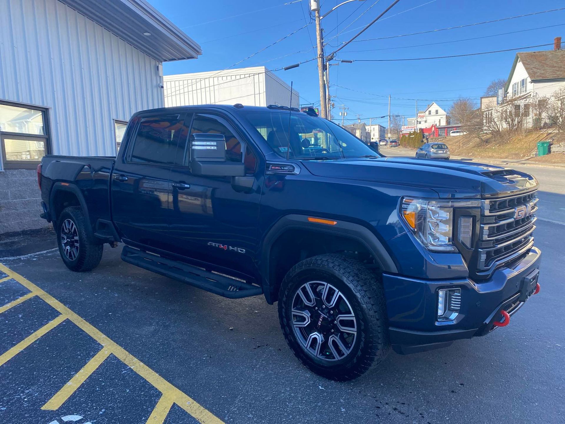 A blue pickup truck is parked in a parking lot in front of a building.