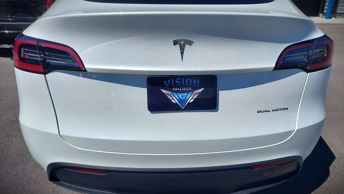 A white Tesla Model 3 is parked in a parking lot.